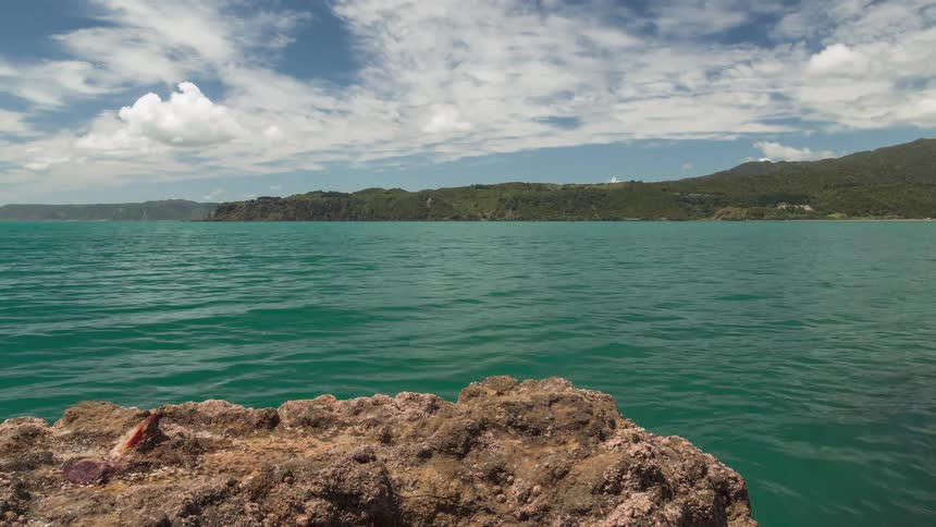 A bay of water next to rocks and there is a concrete pier