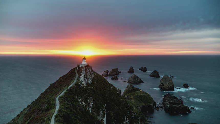 A lighthouse on top of a coastal mountain at dusk