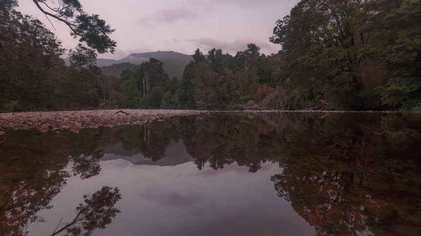 Time lapse of clouds rolling over a lake in the mountains at dusk