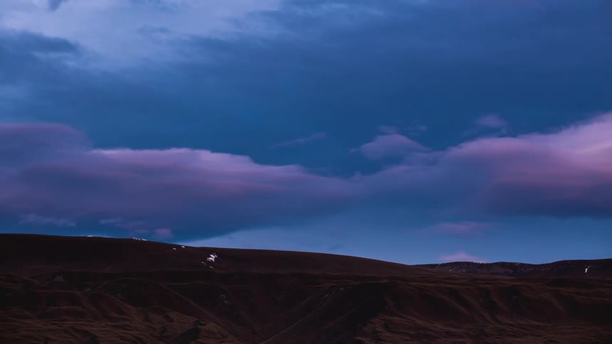 Natural landscape during twilight with dramatic sky where dense clouds pass by as the day darkens