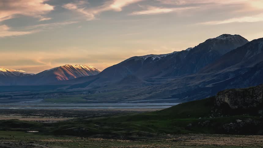 Clouds float over a plain bordered by a mountain range
