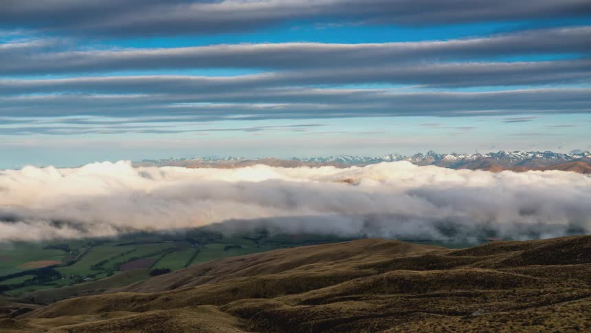 A time lapse of clouds over some hills at dusk