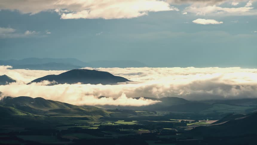 Natural landscape with greenish fields and mountains in a sea of clouds
