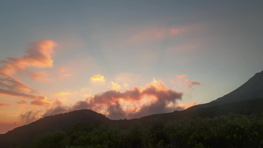 Clouds roil in the sky over a mountain ridge