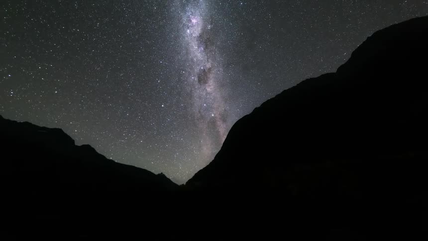 The milky way appearing in the night sky over mountains