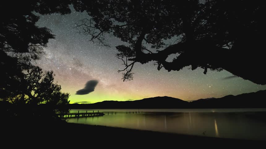 The milky way galaxy visible in the sky over a lake and mountains