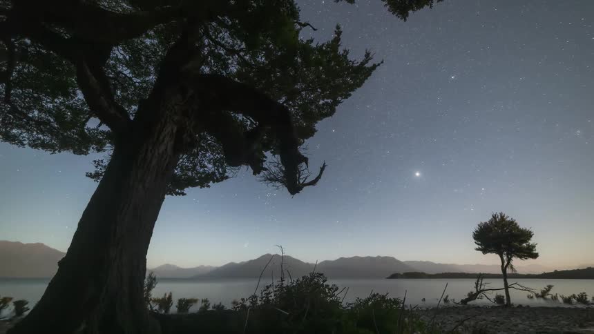 The sun sets and the stars shine over the lake