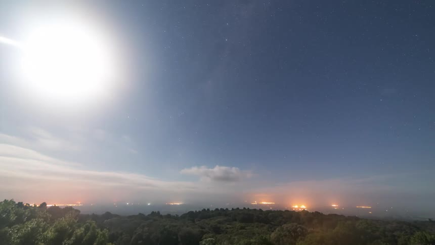 Time lapse of the moon rising over the landscape on a bright starry night