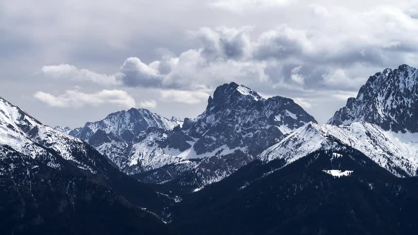 Mountains with snowcapped peaks and clouds passing by