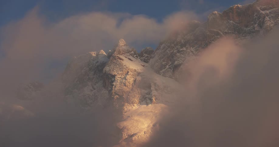 Snowy mountains with clouds passing by in the late afternoon