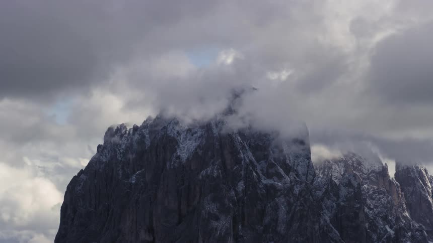 Misty clouds above the snowy peaks of a mountain