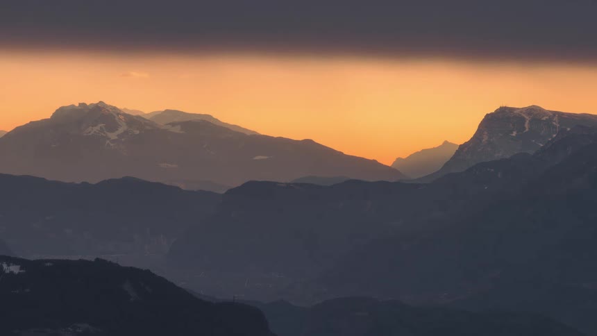 A mountain range on an evening with an orange sky