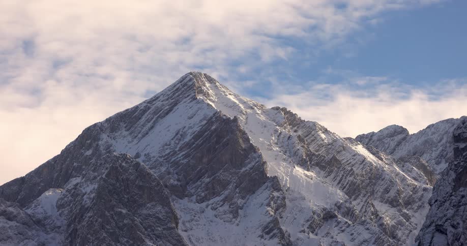Snowy peaks and mountains against a blue sky with clouds