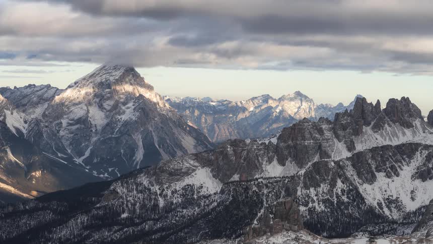 Time lapse of a layer of clouds rolling over the snowcovered slopes of a mountain range