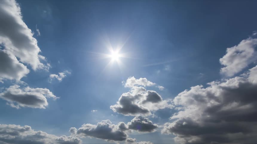 Clear blue sky with scattered white clouds and the sun shining brightly