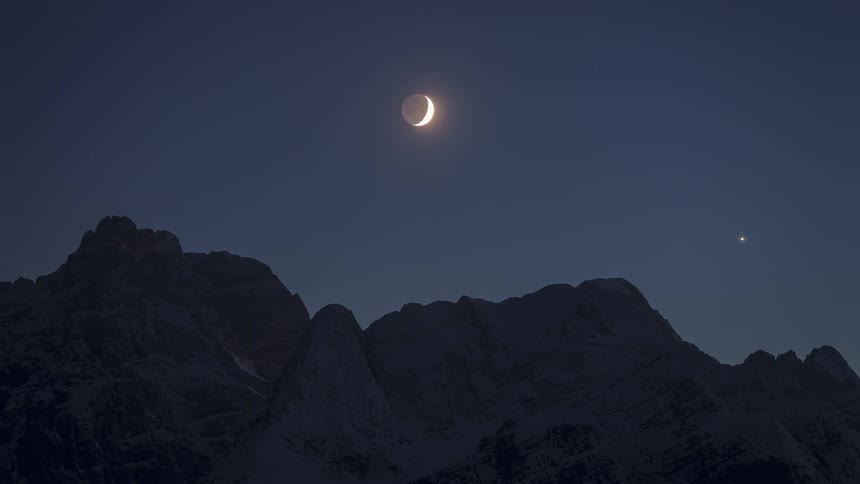 Moon moving above snowy mountains