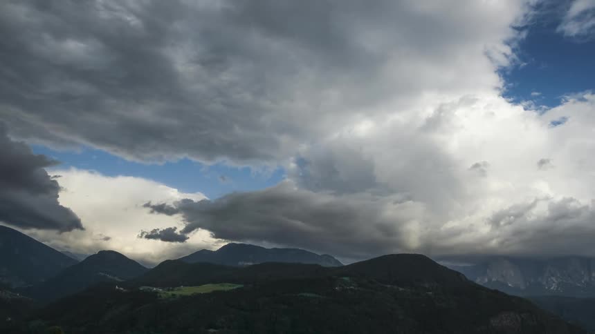 Clouds flow over a forested mountain range during a summer day