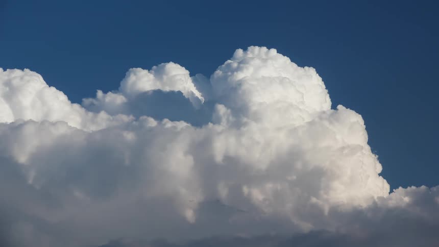 White puffy clouds contrast with the blue of the sky while flowing through the air