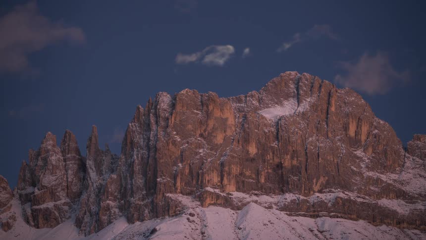 Time lapse of the moon rising over a rocky mountain ridge