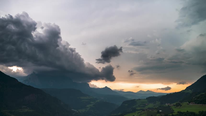 Mountainous landscape at dusk with dramatic clouds and a touch of golden sunlight
