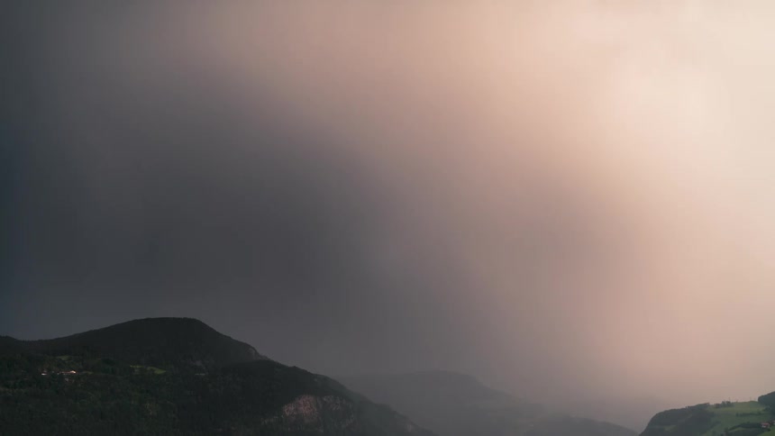 Time lapse of a dramatic sky with sunlight piercing through dark clouds over mountainous terrain