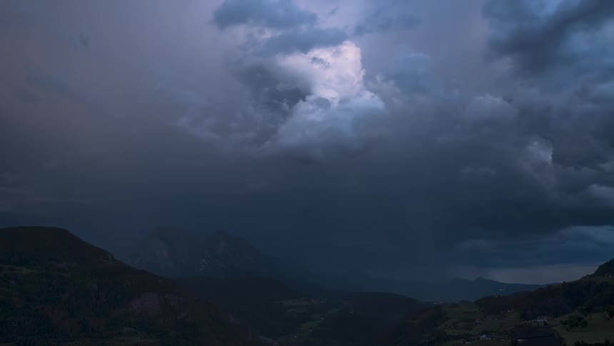 Time lapse of dark clouds rolling over a mountainous landscape at dusk