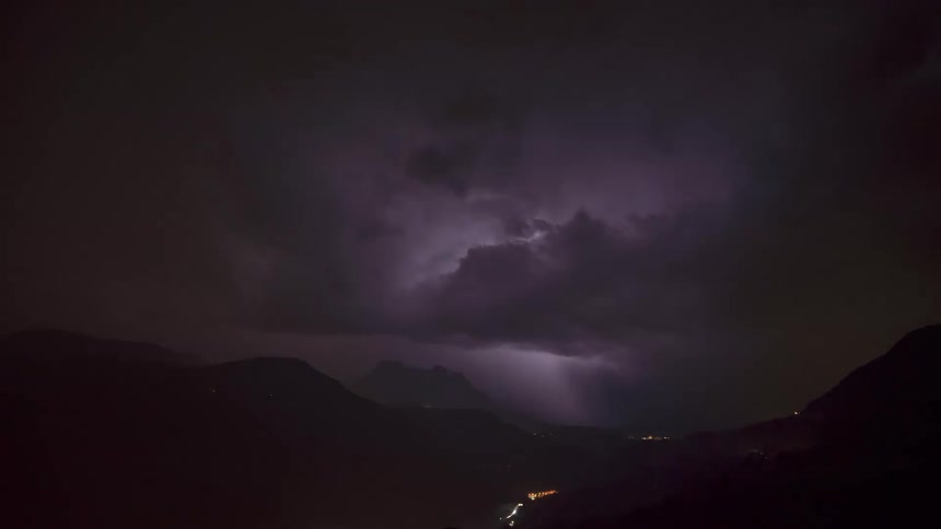 Time lapse of a thunderstorm rolling over a highway next to the mounains at night