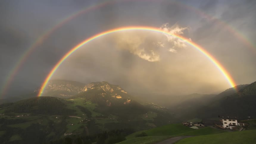 Rainbow amid green mountains on a cloudy day