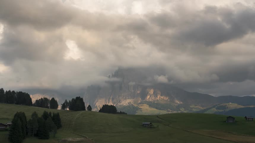 Small wooden houses in greenish mountains on a cloudy day