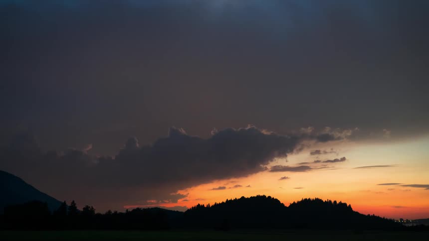 A gigantic storm cloud hovers in the sky over a time lapsed period