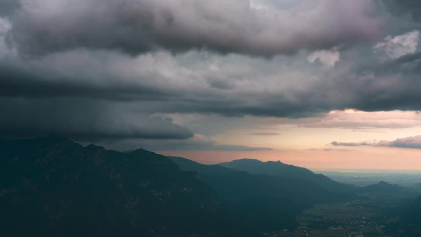 Time lapse of clouds rolling over a valley in the mountains at sunset