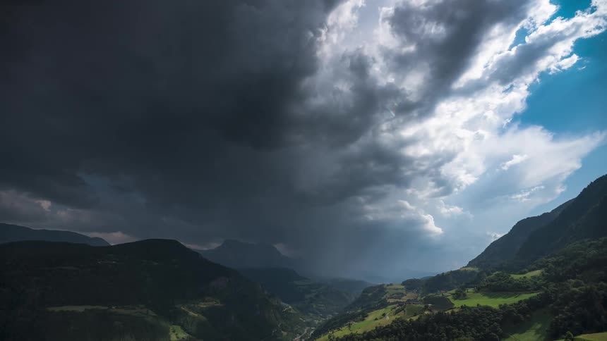 Time lapse of thin clouds rolling over a green valley in the mountains