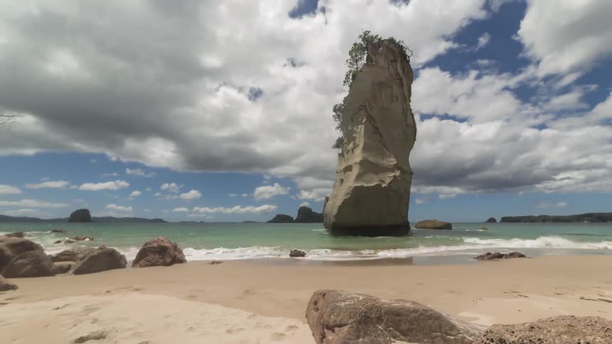 Landscape of rocks on a beach with clouds passing by