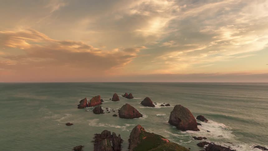 Rocks in the middle of the ocean and an afternoon sky set with clouds