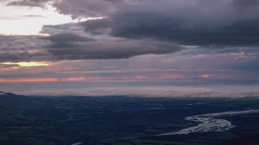 Time lapse of clouds rolling over a landscape at sunset