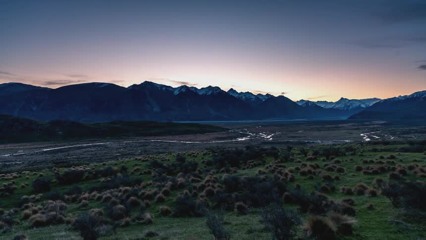 Landscape of a flowing river surrounded by mountains silhouette on a dusk day