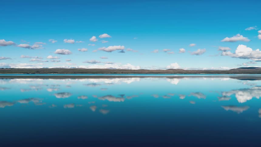 Vast mirrored lake reflecting the blue sky and white clouds