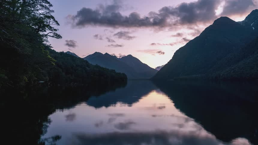 The sun is rising on the lake by the mountains