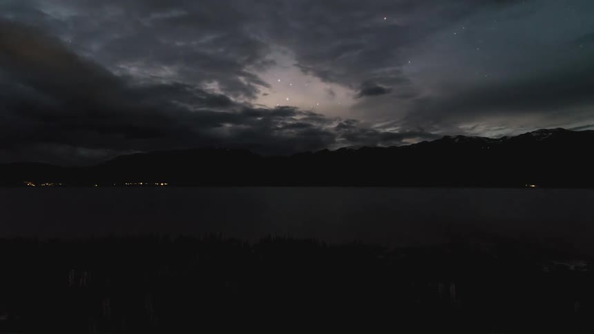 Time lapse of clouds rolling over a placid lake in the mountains