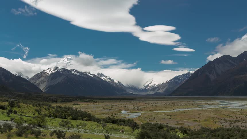 Landscape with mountain ranges covered in snow and a blue sky with clouds passing by