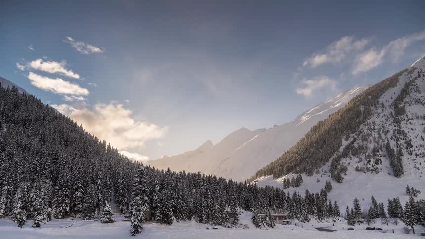 Clouds billow into the sky over a mountain and valley