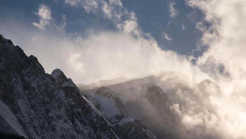 Time lapse of clouds rolling over the snowcovered slopes of a mountain