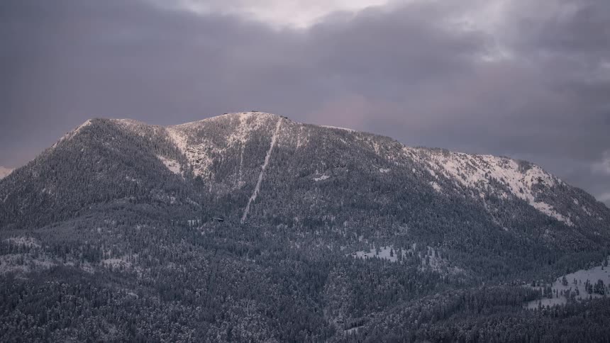 Snowcovered mountain illuminated by a soft light contrasting with the cloudy sky