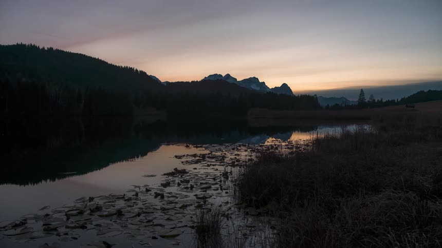 Silhouette of mountains by a lake with the dawn sky