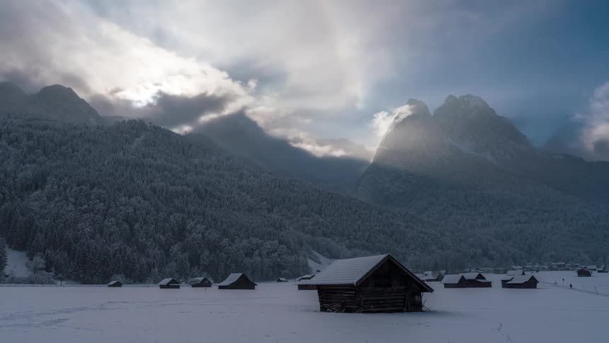 People walk in the snow past the cabins