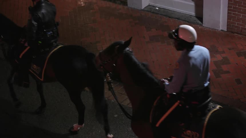 Police officers ride horses through a city