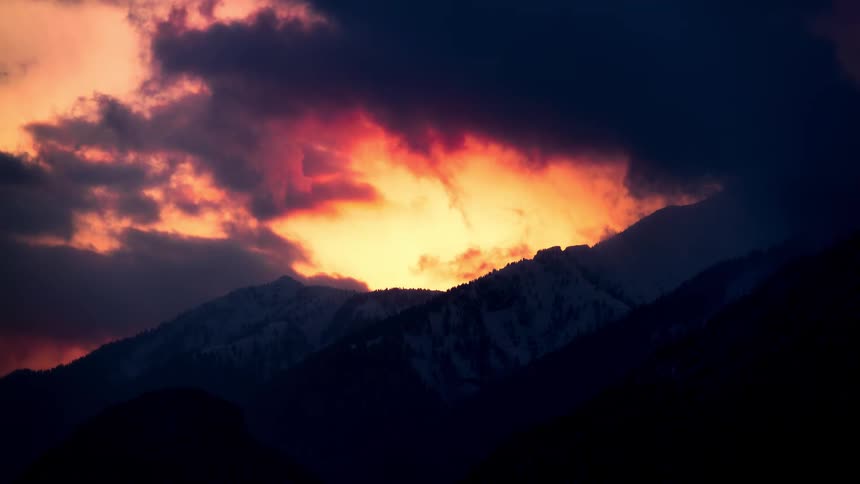 Red sky with clouds above silhouette of mountains