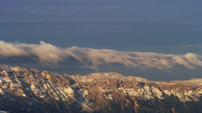 Mountainous landscape with snowcovered rocky peaks under a blue sky with scattered white clouds