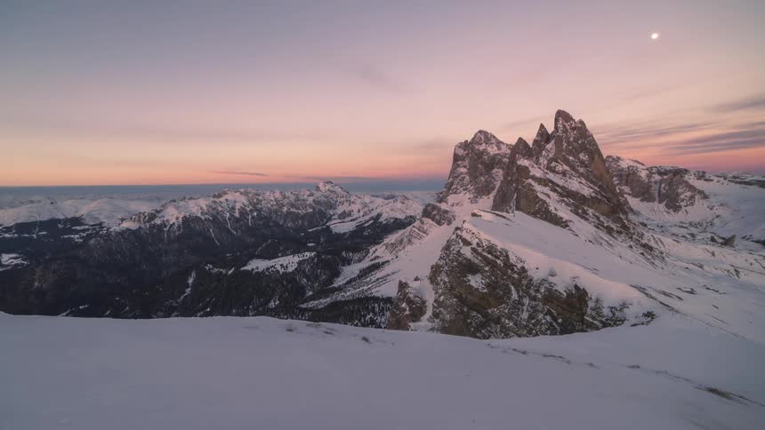 A mountain range covered in snow and its getting dark and the sky is getting dark