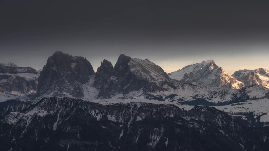 Snowy mountain range with a darkening day